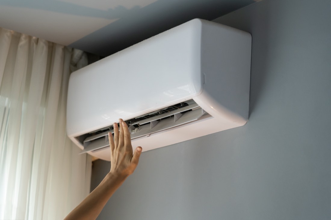 Une main devant une climatisation murale